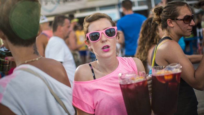 A tourist carries two sangrias at Bora-Bora Bar at the Platja d'en Bossa in Ibiza, Spain