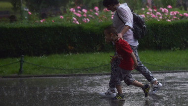 Mamă și copil merg prin ploaie