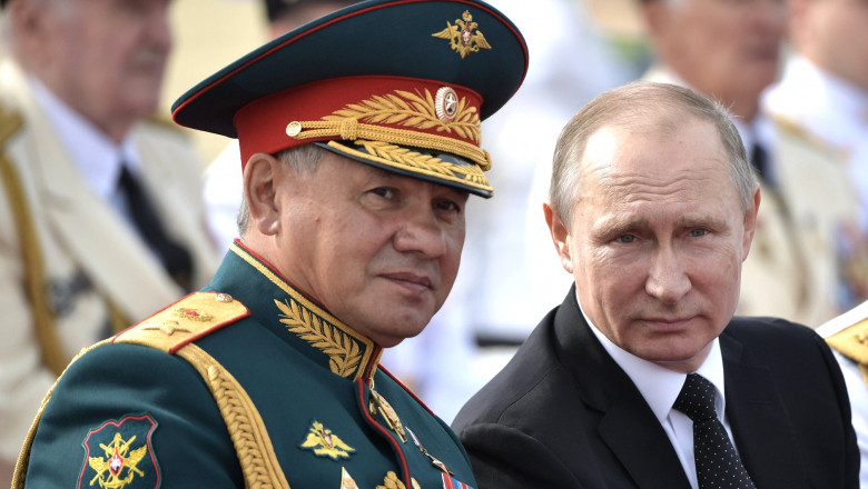 Serghei Șoigu in uniforma si sapca militarași Vladimir Putin in costum