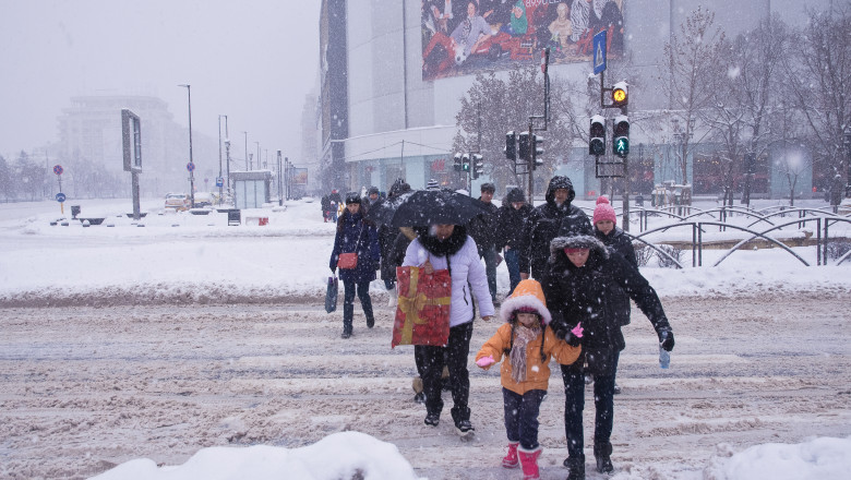 oameni traverseaza stradain bucuresti, de pe trotuare pline de zapada
