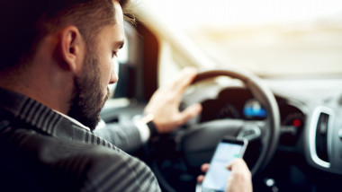 Un șofer folosește telefonul mobil în timp ce se află la volan
