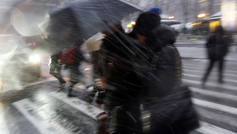 doua femeie circula pe strada pe timp de lapovita si ninsoare.