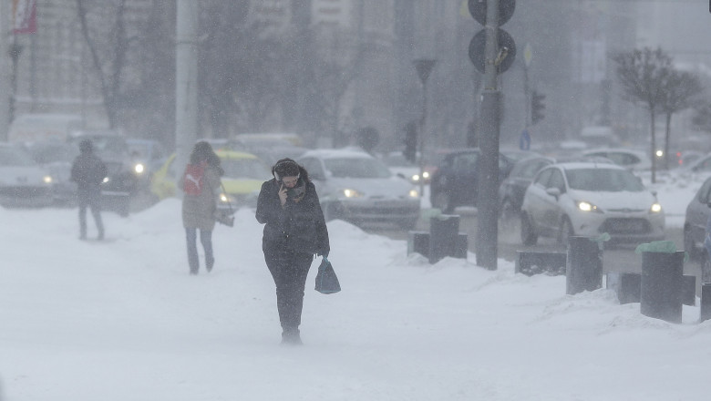 o femeie merge pe strada pe timp de ninsoare puternica.