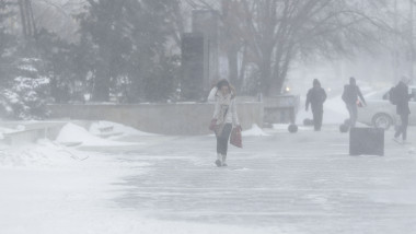 oameni merg pe strada pe viscol si ninsori