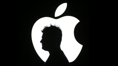 silueta unui barbat in fata logo-ului apple.