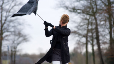 O femeie se protejeaza de vant cu umbrela