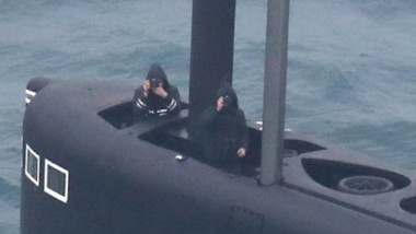 Peisaj acvatic. În largul mării, doi bărbați fac fotografii de pe puntea unui submarin Krasnodar.