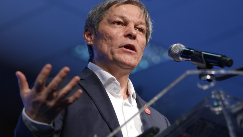 Dacian Cioloș vorbește la microfon gesticuland