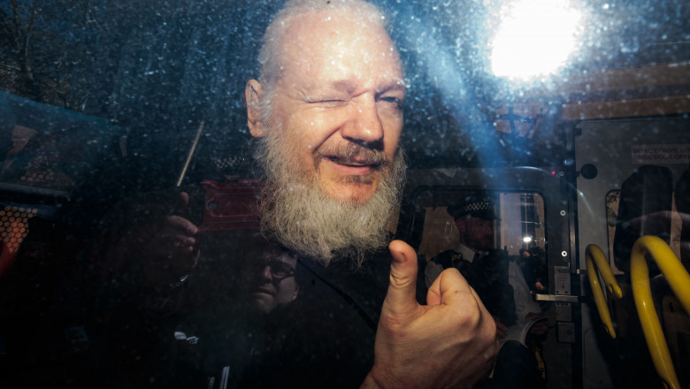 Julian Assange adus la tribunal după arestarea la Londra zambeste face cu ochiul si semn de ok cu mana