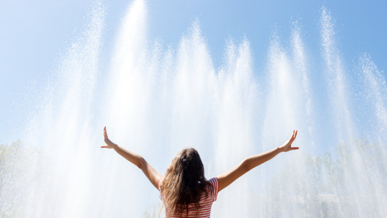 girl happy sunny day andhands up in the background of the fountain, feeling freedom