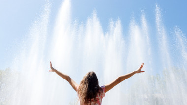 girl happy sunny day andhands up in the background of the fountain, feeling freedom