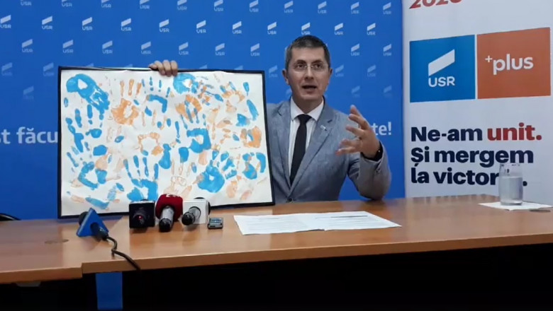 Dan Barna arata un tablou cu urmele unor maini albastre si portocalii imprimate pe panza
