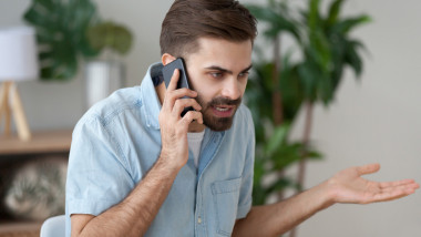 Angry man talking on smartphone solving work problem