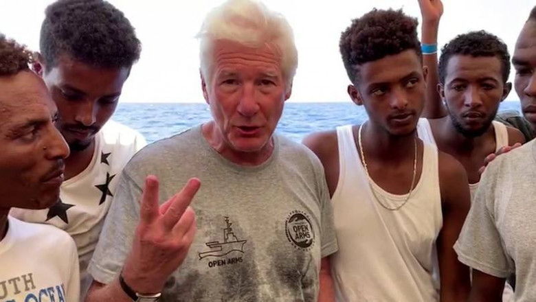 U.S. actor Gere gestures surrounded by rescued migrants aboard Open Arms rescue boat at Mediterranean sea in this screen grab taken from video