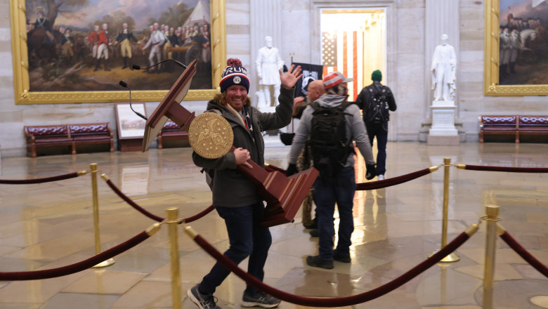 Un susținător al lui Donald Trump cară un pupitru din Capitoliu. Foto: GettyImages