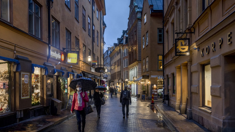 Trecători, unii cu mască, pe străzile din Stockholm, capitala Suediei.