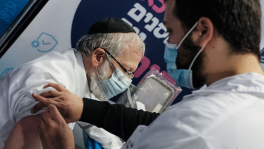 un barbat cu masca vaccineaza un alt barbat cu masca in israel
