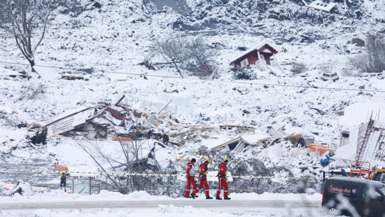 echipa de interventie pe drum in fata unor case distruse pe dealul surpat si inzapezit