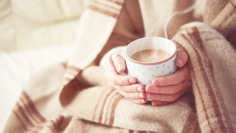 i femeie bea o cana cu cafea calda pentru a se incalzi