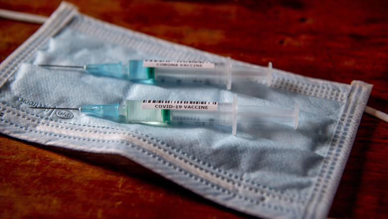 seringi de vaccin anticovid puse pe o masca