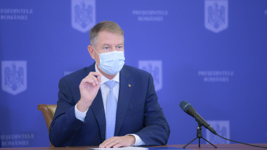 Klaus iohannis cu masca de protectie gesticuleaza in timpul unei conferințe de presă