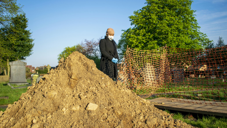 o femeie se reculege lângă un mormant proaspat, in cimitir