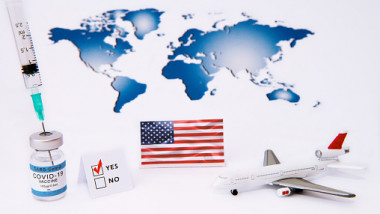 Ilustrație: harta lumii, steagul SUA, avion de jucărie și doze de vaccin
