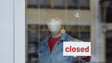 O femeie cu mască își închide magazinul