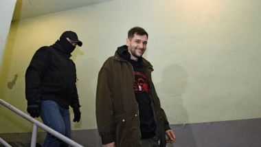 oleg navalnii rade in timp ce este insotit de un politist rus dupa perchezitii