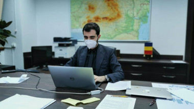 Ministrul Economiiei, Claudiu Năsui, este fotografiat in birou, lucrand la laptop si purtand masca de protectie