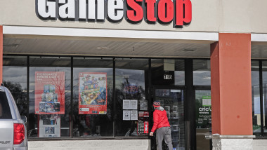 un om in bluza rosie intra intr-un magazin de jocuri online gamestop