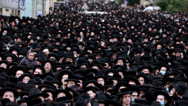 mii de evrei ultraortodocsi inghesuiti unul intr-altul cu palarii negre si fara masca la funeraliile unui rabin, pe strazile din ierusalim