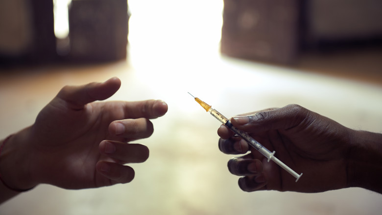 mana unei persoane tinand o seringă cu drog pe care o înmânează altei persoane