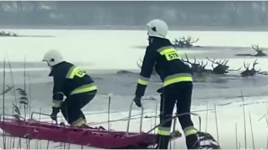 pompieri intr-o barca pe un lac pe jumatate inghetat in apele caruia se vad mai multe perechi de coarne ale unor cerbi care au cazut in apa