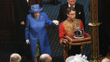 regina elisabeta a II-a impreuna cu printul charles merg in spatele unui oficial care duce coroana britanica