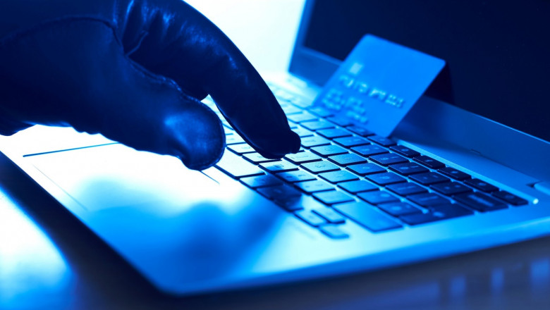 Un infractor cibernetic tastează datele unui card de credit furat pe un laptop