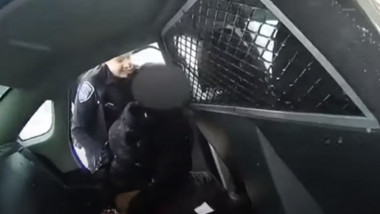 O polițistă urcă o fetiță incătușată în mașină