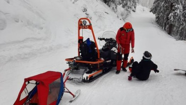 salvamontist cu snowmobil recupereaza un schior ramas blocat pe o partie inalta