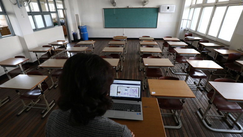banci intr-o sala de clasa si profesorul cu un laptop la catedra