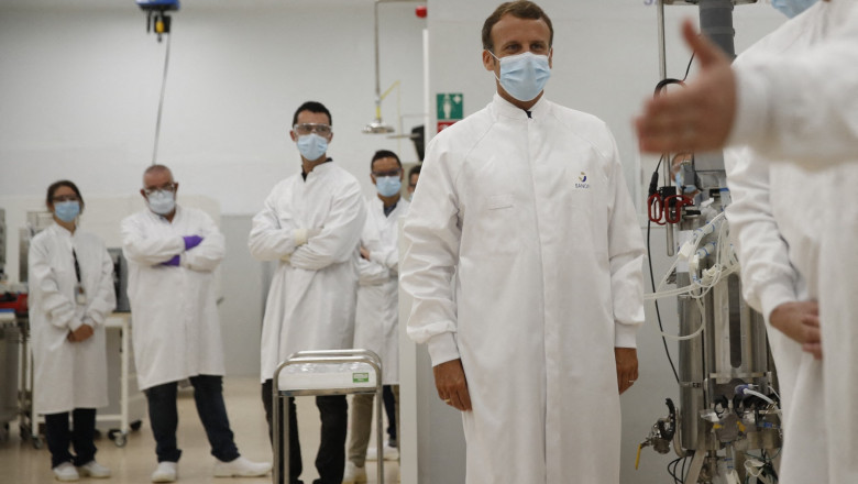 presedintele frantei emmanuel macron cu un halat alb si masca, intr-un spital, inconjurat de cadre medicale
