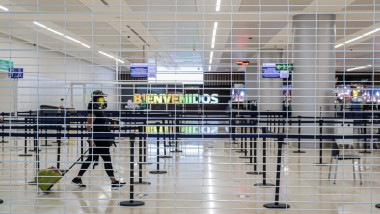 un turist trece cu bagajul prin aeroportul din cancun. imagine vazuta printre gratii