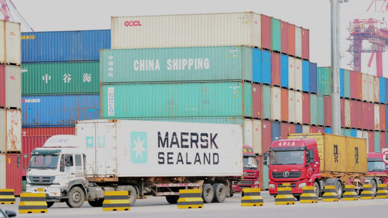 Camioane care transportă containere de marfă în port.