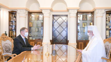 întâlnire între Klaus Iohannis şi patriarhul Daniel. Cei doi stau la masă, faţă în faţă, fiecare cu masca de protecţie pe faţă