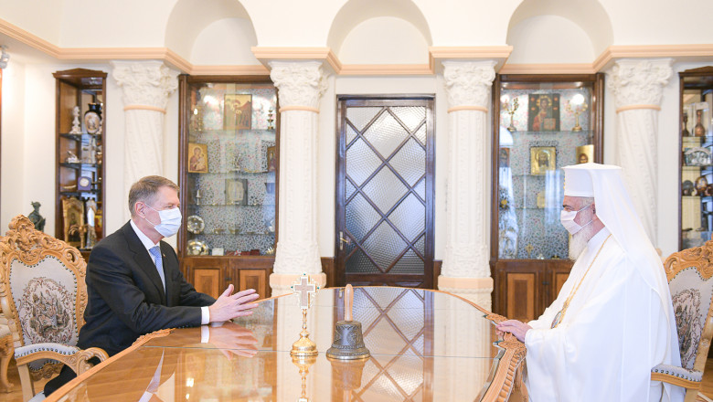 întâlnire între Klaus Iohannis şi patriarhul Daniel. Cei doi stau la masă, faţă în faţă, fiecare cu masca de protecţie pe faţă