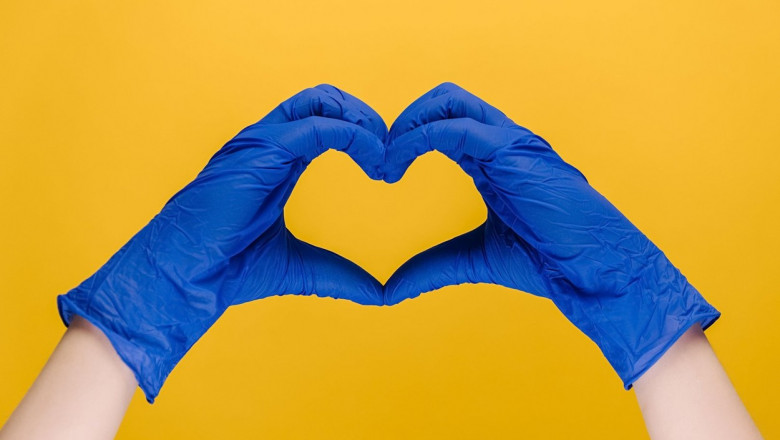 doua maini cu manusi chirurgicale albastre care formeaza o inima