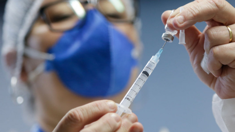 Un cadru medical umple o seringă cu ser dintr-o doza de vaccin.