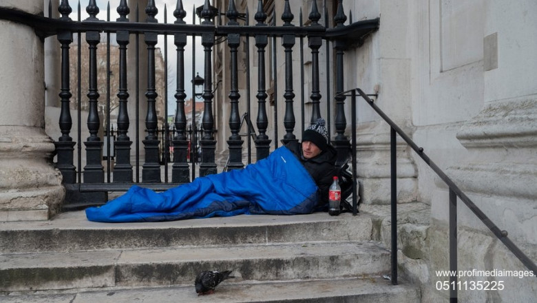 Persoană fără adăpost pe scările unei clădiri.