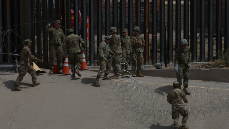 Militari americani lucrează la zidul de la frontiera dintre SUA și Mexic.