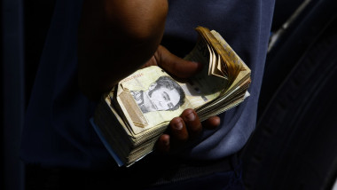 mana unui barbat tine un teanc de bancnote in venezuela asteptand sa cumpere ceva