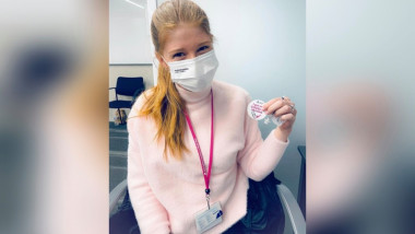 Fiica lui gates după vaccinare, tinand in mana un autocolant pe care scrie „Am primit vaccinul meu împotriva Covid-19”